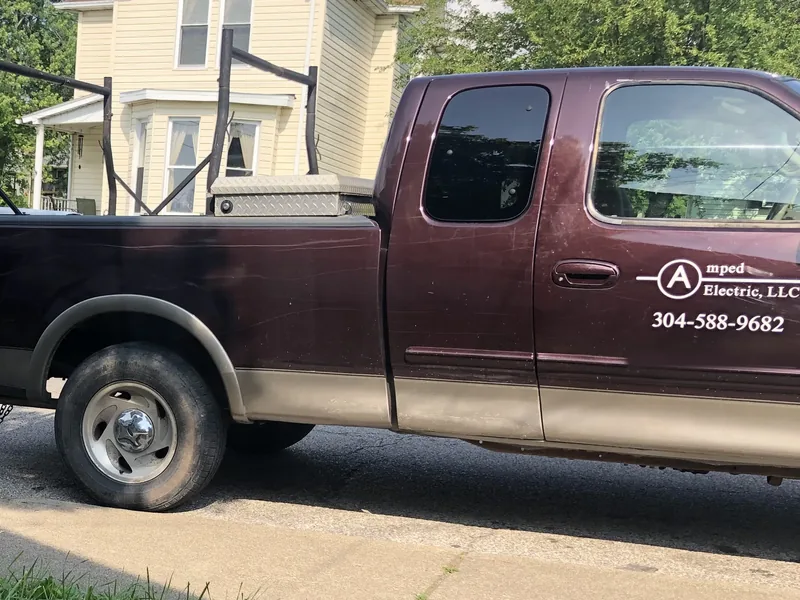 Amped Electric work truck with the company name and phone number on the door