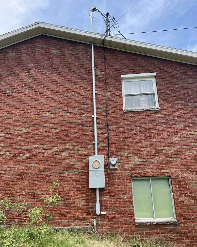 Exterior service mast, conduit and meter on the brick wall of a house